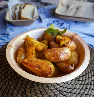 Roasted potatoes served in a palm leaf bowl on a set table
