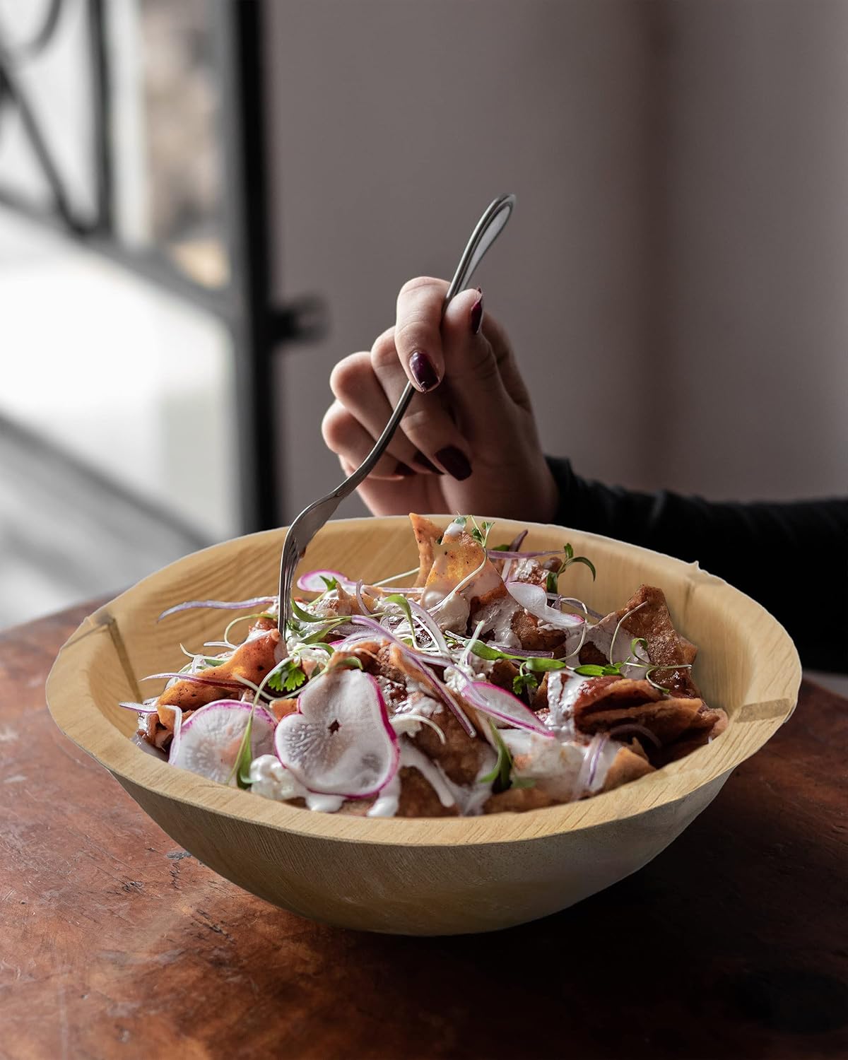 person eating a salad from a large 8.5 inch palm leaf bowl